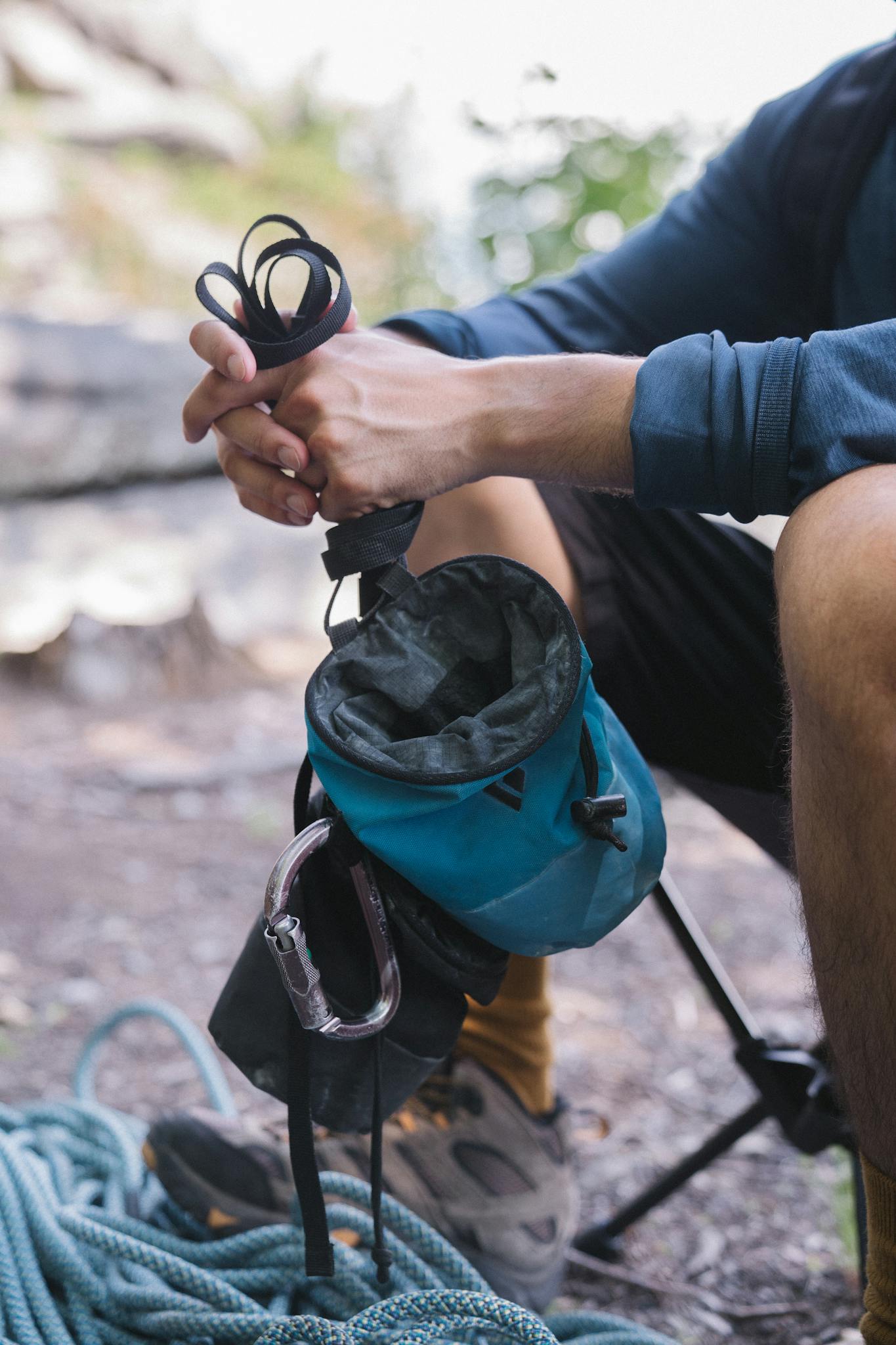 Climber holds chalk bag and rope outdoors, ready for a climbing adventure.