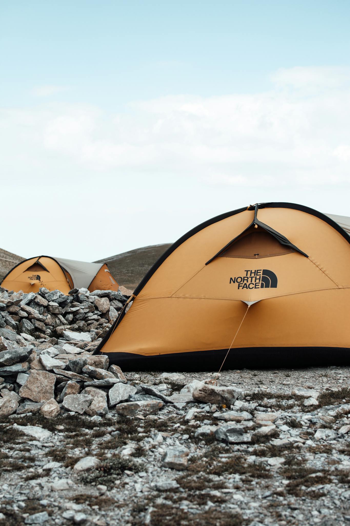 Orange tents on rocky ground, ideal for outdoor camping or hiking adventures.